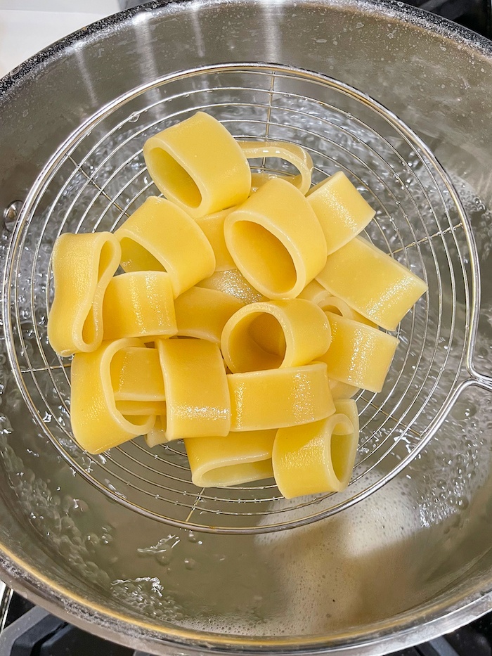 Removing calamarata pasta with a slotted spoon