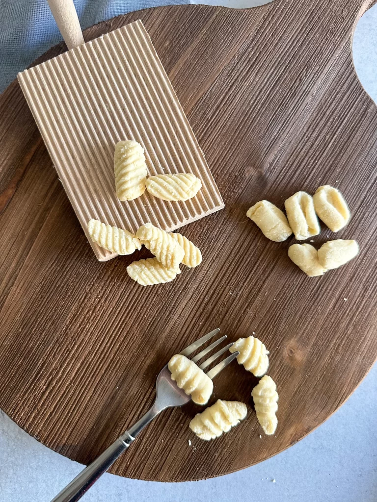 3 methods to shape cavatelli shown on a wood round board